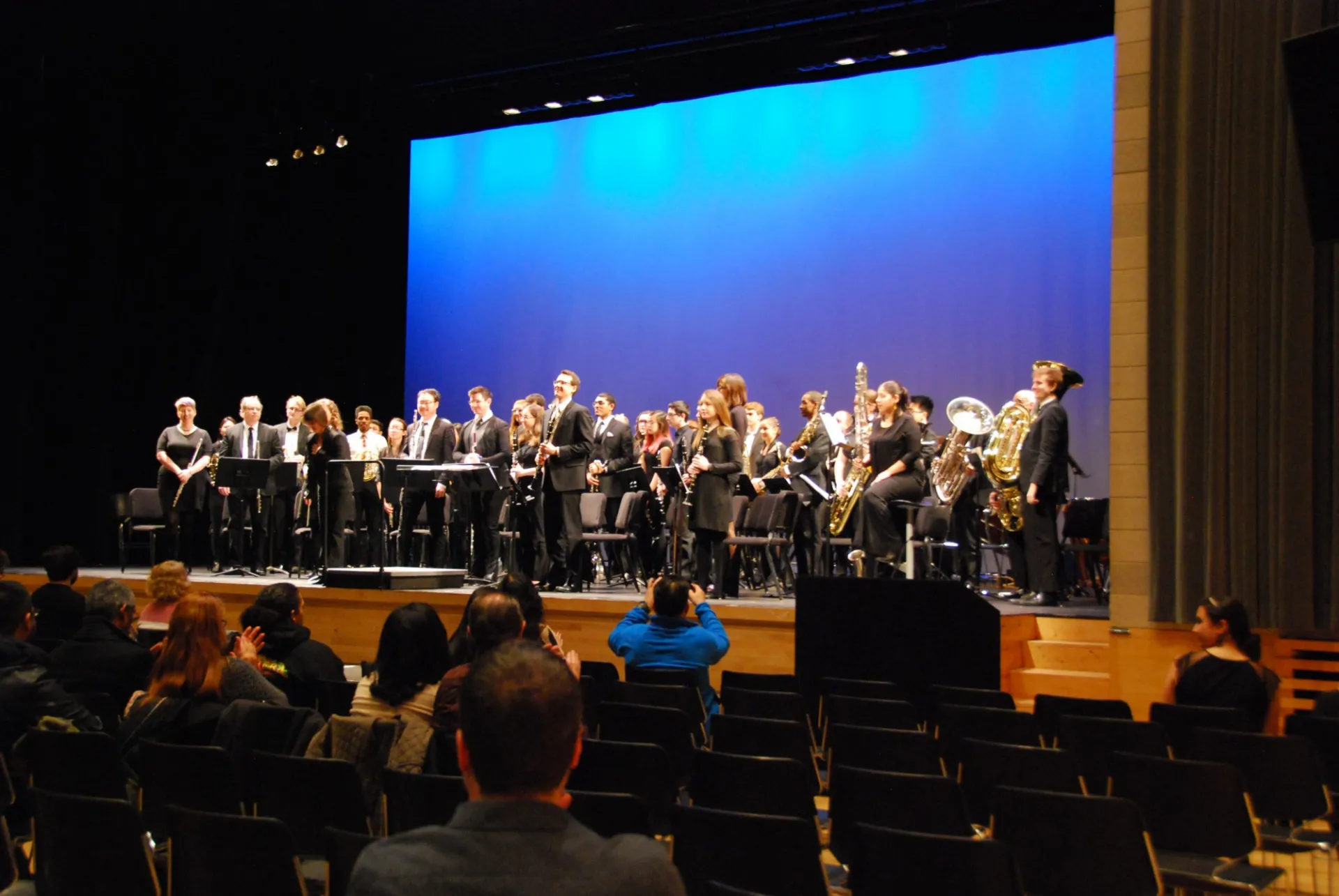The Wind Ensemble stands on stage as the audience applauds after a Festival of Winds performance.