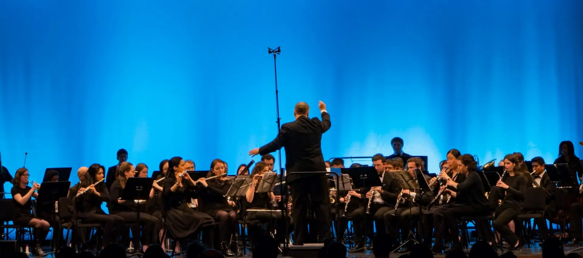 The CUWE conductor gives a dramatic cue onstage.
