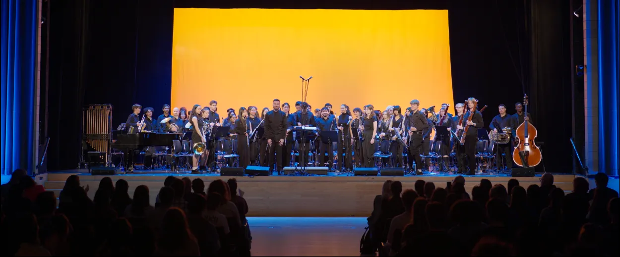 The Columbia University Wind Ensemble stands on stage.
