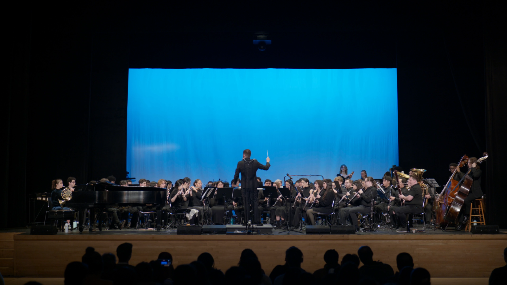 CUWE performs onstage, members play their instruments as the conductor gives a cue.